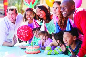 Multi-ethnic group of children and parents at little girl's birthday party.