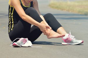 Young woman suffering from an ankle injury while exercising and running