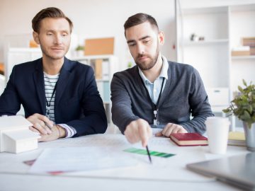 Portrait of real estate agent helping client choosing house in agency