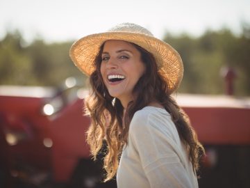 Portrait cheerful young woman wearing sun hat at farm